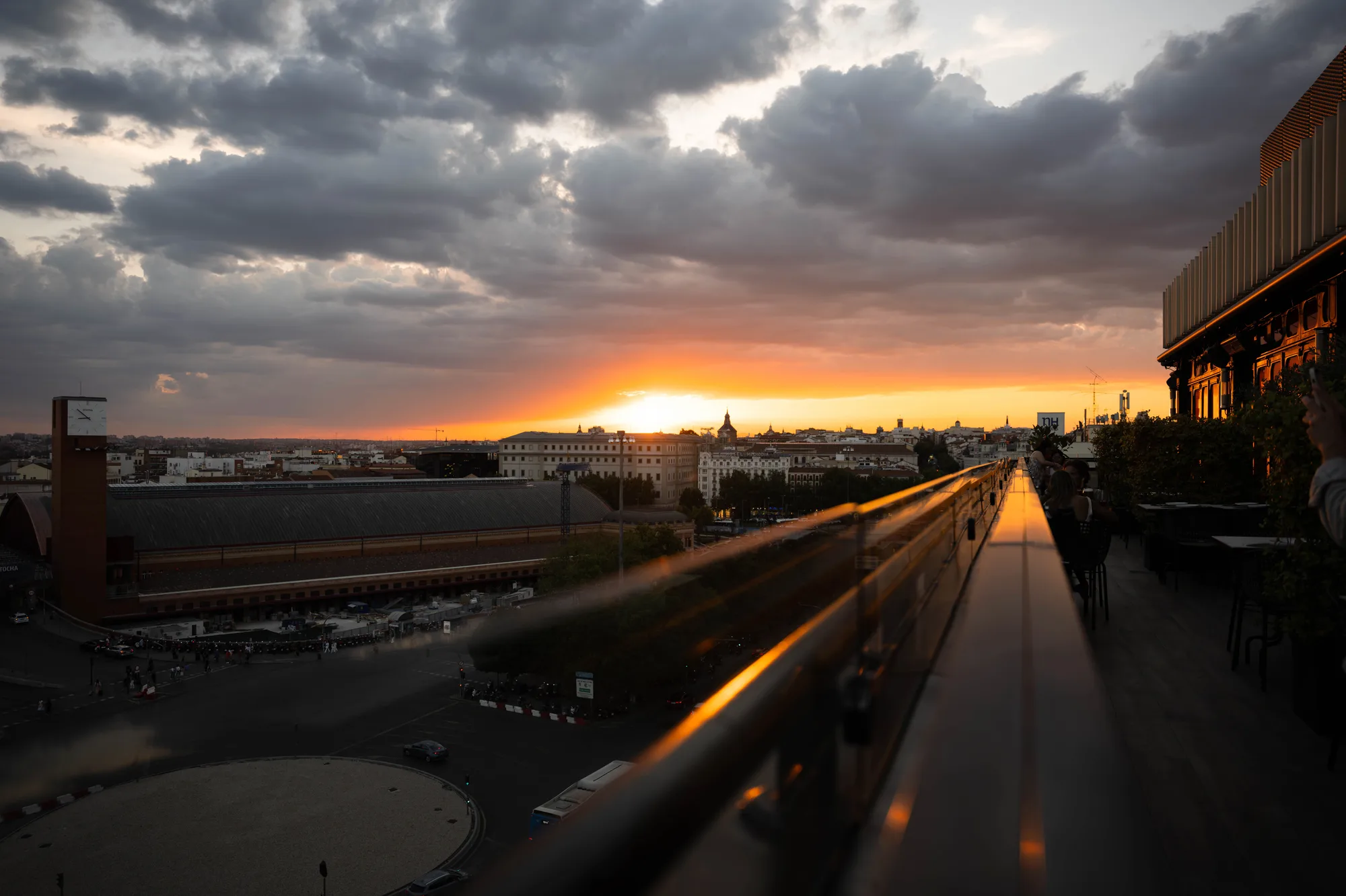 Sunset breaking beneath storm clouds over a city rail station
